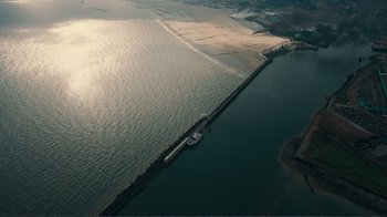 Movie still from “Dunkirk” (2017), directed by Christopher Nolan – An aerial view of a body of water with a boat in it; Extreme Wide shot, High angle