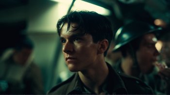 Movie still from “Dunkirk” (2017), directed by Christopher Nolan – A young man in a military uniform looking into the distance; Close Up shot, Low angle