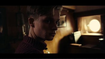 Movie still from “Dunkirk” (2017), directed by Christopher Nolan – A young man in a red sweater is looking at the camera; Close Up shot, Low angle