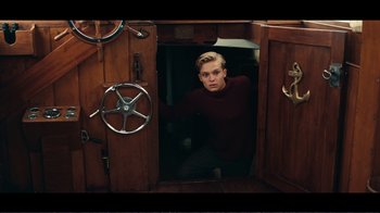Movie still from “Dunkirk” (2017), directed by Christopher Nolan – A young man standing in a doorway of a boat; Medium shot, High angle