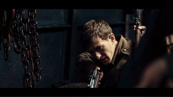 Movie still from “Dunkirk” (2017), directed by Christopher Nolan – A man holding a gun in his hand; Medium shot, Over the shoulder angle