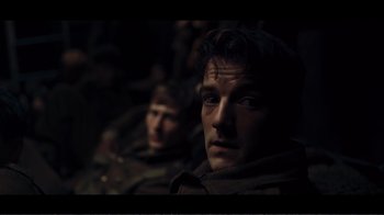 Movie still from “Dunkirk” (2017), directed by Christopher Nolan – A man in a trench coat looking into the camera; Close Up shot, Over the shoulder angle