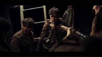 Movie still from “Dunkirk” (2017), directed by Christopher Nolan – Two young men are standing in a dark room; Medium shot, Over the shoulder angle