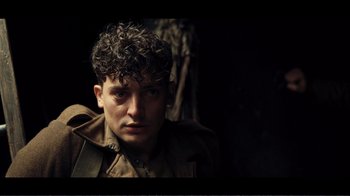 Movie still from “Dunkirk” (2017), directed by Christopher Nolan – A young man with curly hair is posing for a picture; Close Up shot, Over the shoulder angle