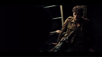 Movie still from “Dunkirk” (2017), directed by Christopher Nolan – A man in a brown jacket holding a stick; Medium shot, Over the shoulder angle