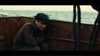 Movie still from “Dunkirk” (2017), directed by Christopher Nolan – A man sitting in a boat on the water; Medium shot, Over the shoulder angle