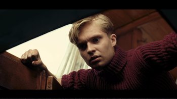 Movie still from “Dunkirk” (2017), directed by Christopher Nolan – A young man in a red sweater looking at the camera; Medium shot, Low angle