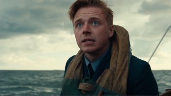 Movie still from “Dunkirk” (2017), directed by Christopher Nolan – A man with blue eyes looking up into the sky; Close Up shot, Over the shoulder angle