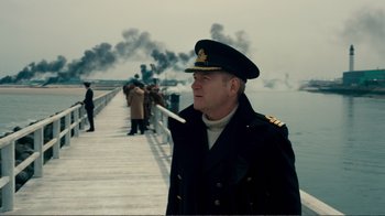 Movie still from “Dunkirk” (2017), directed by Christopher Nolan – A man in a military uniform smoking a cigarette; Medium shot, Over the shoulder angle