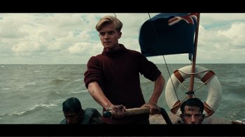 Movie still from “Dunkirk” (2017), directed by Christopher Nolan – A man in a sweater on a boat in the ocean; Medium shot, Low angle