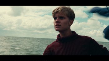 Movie still from “Dunkirk” (2017), directed by Christopher Nolan – A man in a red sweater looks at the ocean; Close Up shot, Low angle