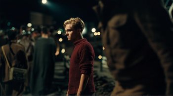 Movie still from “Dunkirk” (2017), directed by Christopher Nolan – A man in a red sweater standing in the dark; Medium shot, Over the shoulder angle
