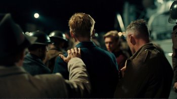 Movie still from “Dunkirk” (2017), directed by Christopher Nolan – A group of people standing around each other in the dark; Medium shot, Over the shoulder angle