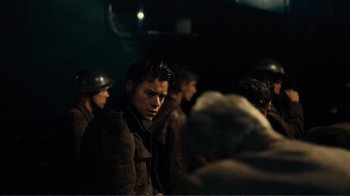 Movie still from “Dunkirk” (2017), directed by Christopher Nolan – A group of men in military fatigues and helmets; Medium shot, Over the shoulder angle