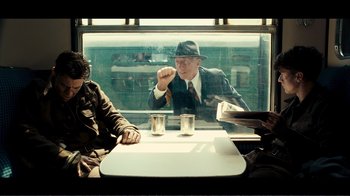 Movie still from “Dunkirk” (2017), directed by Christopher Nolan – A man sitting at a table in front of a window; Medium shot, Over the shoulder angle