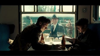 Movie still from “Dunkirk” (2017), directed by Christopher Nolan – A group of men sitting at a table in front of a window; Medium shot, Over the shoulder angle