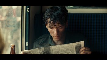 Movie still from “Dunkirk” (2017), directed by Christopher Nolan – A man reading a newspaper while sitting on a train; Close Up shot, Over the shoulder angle