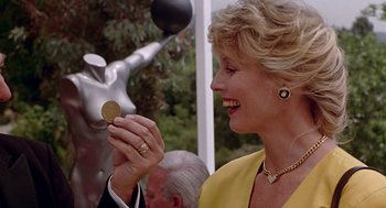 Movie still from “Pretty Woman” (1990), directed by Garry Marshall – A woman in a yellow dress holding a gold coin; Close Up shot, Over the shoulder angle