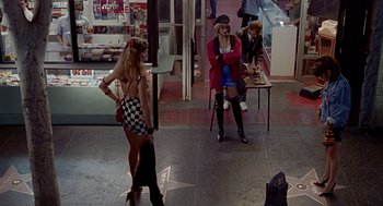 Movie still from “Pretty Woman” (1990), directed by Garry Marshall – A woman in a short skirt is standing in front of two other women; Wide shot, High angle