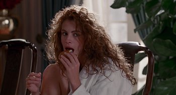Movie still from “Pretty Woman” (1990), directed by Garry Marshall – A woman eating a donut while sitting on a chair; Medium shot, Over the shoulder angle