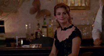 Movie still from “Pretty Woman” (1990), directed by Garry Marshall – A woman sitting at a bar wearing a black dress; Medium shot, Over the shoulder angle