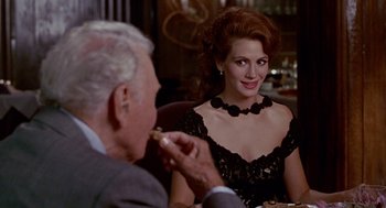 Movie still from “Pretty Woman” (1990), directed by Garry Marshall – An older man sitting next to a woman in a black dress; Medium shot, Over the shoulder angle