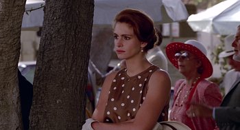 Movie still from “Pretty Woman” (1990), directed by Garry Marshall – A woman in a brown polka dot dress standing next to a tree; Medium shot, Over the shoulder angle