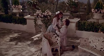 Movie still from “Pretty Woman” (1990), directed by Garry Marshall – A man kneeling down next to a woman in front of a chair; Wide shot, High angle