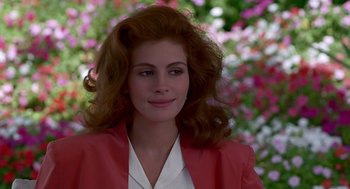 Movie still from “Pretty Woman” (1990), directed by Garry Marshall – A woman in a red jacket is smiling for the camera; Close Up shot, Over the shoulder angle