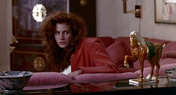Movie still from “Pretty Woman” (1990), directed by Garry Marshall – A woman sitting on top of a couch in a living room; Medium shot, Low angle