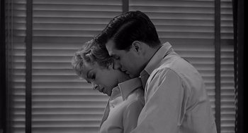 Movie still from “Psycho” (1960), directed by Alfred Hitchcock – A man and a woman embracing each other in front of a window; Medium shot, Low angle