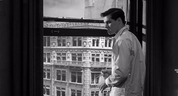 Movie still from “Psycho” (1960), directed by Alfred Hitchcock – A man standing in front of a large window; Medium shot, Low angle