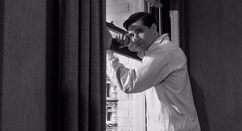 Movie still from “Psycho” (1960), directed by Alfred Hitchcock – A black and white photo of a man holding a gun; Medium shot, Low angle