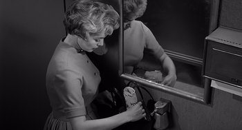 Movie still from “Psycho” (1960), directed by Alfred Hitchcock – A woman holding a clock in front of a bathroom mirror; Medium shot, Low angle