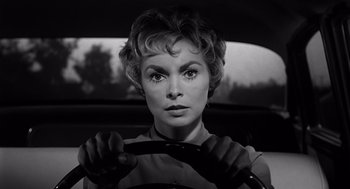 Movie still from “Psycho” (1960), directed by Alfred Hitchcock – A woman sitting in a car holding a steering wheel; Close Up shot, Low angle