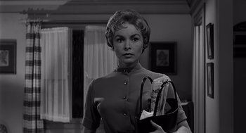 Movie still from “Psycho” (1960), directed by Alfred Hitchcock – A black and white photo of a woman holding a purse; Medium shot, Low angle