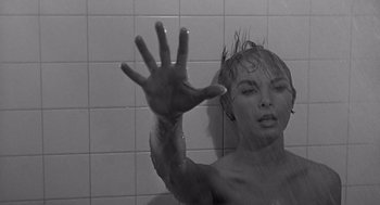 Movie still from “Psycho” (1960), directed by Alfred Hitchcock – A black and white photo of a woman taking a shower; Close Up shot, Low angle