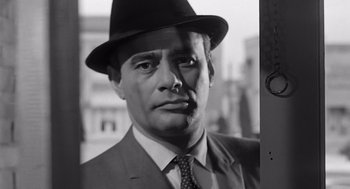 Movie still from “Psycho” (1960), directed by Alfred Hitchcock – Black and white photograph of a man wearing a suit and hat; Close Up shot, Low angle