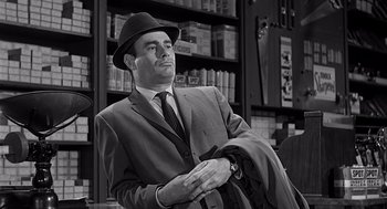 Movie still from “Psycho” (1960), directed by Alfred Hitchcock – A black and white photo of a man in a suit and hat holding a suit jacket; Medium shot, Low angle