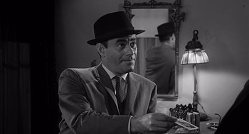 Movie still from “Psycho” (1960), directed by Alfred Hitchcock – A black and white photo of a man wearing a hat; Close Up shot, Over the shoulder angle