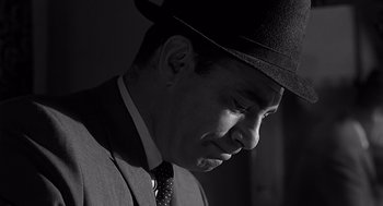 Movie still from “Psycho” (1960), directed by Alfred Hitchcock – A black and white photo of a man in a suit and hat; Close Up shot, Low angle