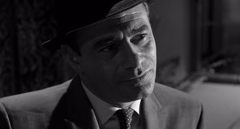 Movie still from “Psycho” (1960), directed by Alfred Hitchcock – Black and white photograph of a man in a suit and hat; Close Up shot, High angle