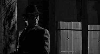 Movie still from “Psycho” (1960), directed by Alfred Hitchcock – A black and white photo of a man in a suit and hat; Close Up shot, Low angle