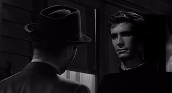 Movie still from “Psycho” (1960), directed by Alfred Hitchcock – A man wearing a hat looking at another man in front of a window; Close Up shot, Over the shoulder angle