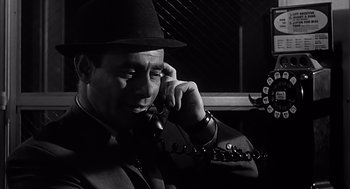 Movie still from “Psycho” (1960), directed by Alfred Hitchcock – A black and white photo of a man talking on a phone; Close Up shot, Low angle