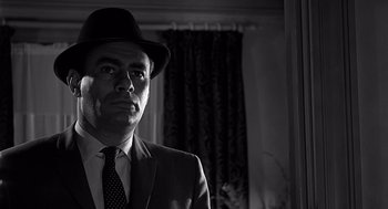 Movie still from “Psycho” (1960), directed by Alfred Hitchcock – A black and white photo of a man in a suit and hat; Close Up shot, Low angle