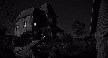 Movie still from “Psycho” (1960), directed by Alfred Hitchcock – A house that has been lit up at night time; Extreme Wide shot, Low angle