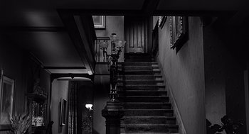 Movie still from “Psycho” (1960), directed by Alfred Hitchcock – A black and white photo of a staircase in a house; Wide shot, High angle