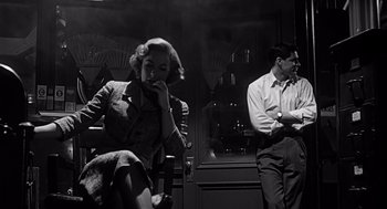 Movie still from “Psycho” (1960), directed by Alfred Hitchcock – A man and a woman sitting next to each other in front of a building; Medium shot, Low angle