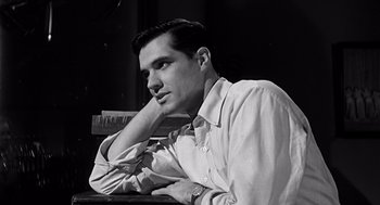 Movie still from “Psycho” (1960), directed by Alfred Hitchcock – Black and white photograph of a man leaning on a table; Close Up shot, Low angle